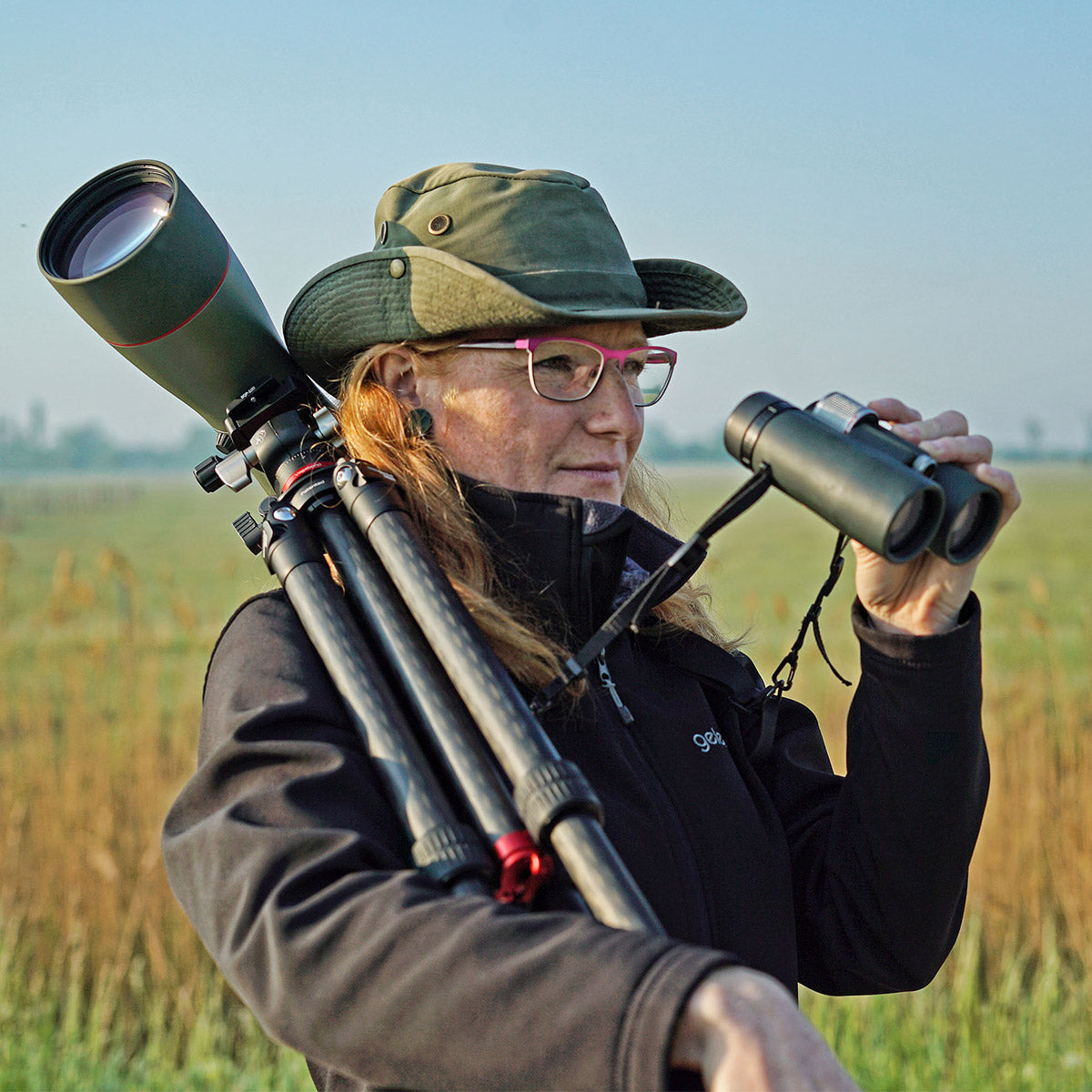 Woman using Kowa TSN-88A PROMINAR 25-60x Angled Spotting Scope Kit on a tripod in a serene outdoor setting.